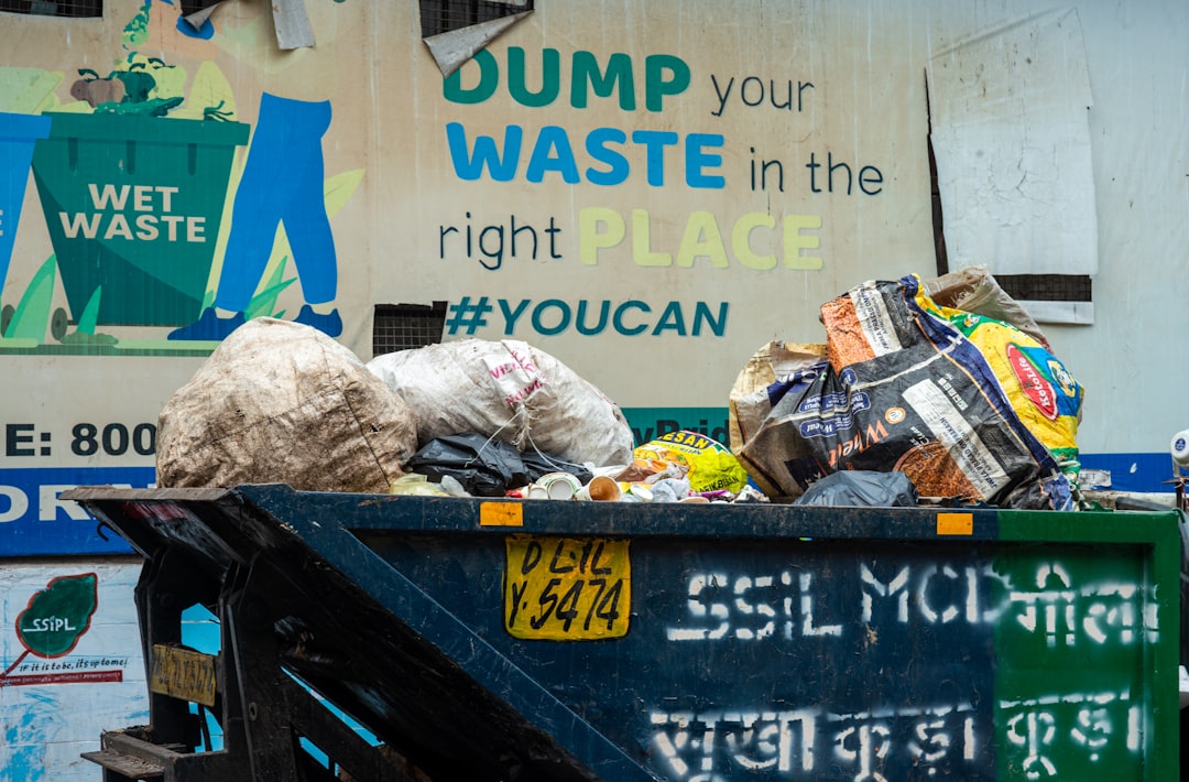 Overflowing dumpster with trash and a sign | The National Recycling Corporation