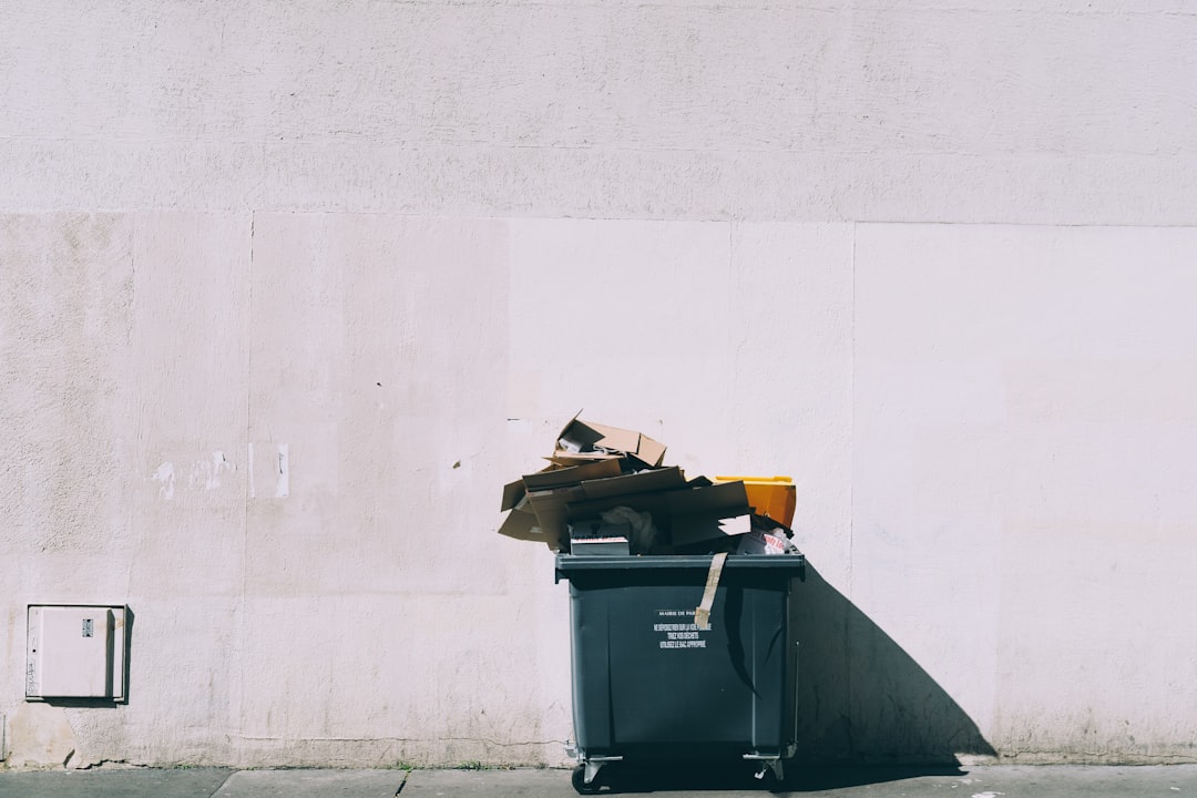 black plastic garbage bin with wheels beside wall | The National Recycling Corporation